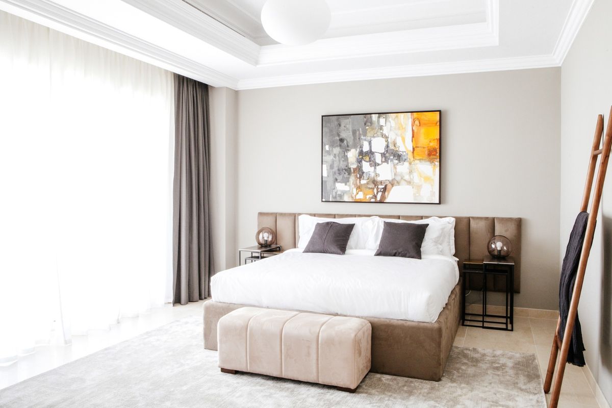 Bedroom with an upholstered headboard, bench and lined curtains