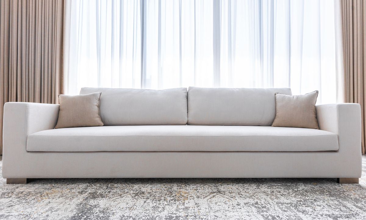 White three-seater sofa in front of sheer curtains